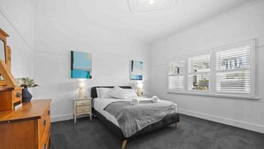 A bedroom with a bed, bedside tables, a dresser, and a window with blinds. - House on Drummond - A large home close to the heart of central Ballarat (Ballarat Central)
