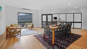 A modern dining area with a wooden table and chairs, a patterned rug, and a view through a large window. - House on Drummond - A large home close to the heart of central Ballarat (Ballarat Central)