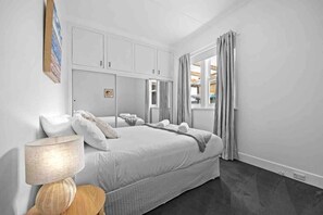 A modern bedroom with a large bed, a bedside table with a lamp, and a wardrobe.
