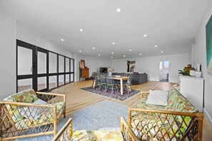 A spacious living area with a dining table, two sofas, and a kitchen area.