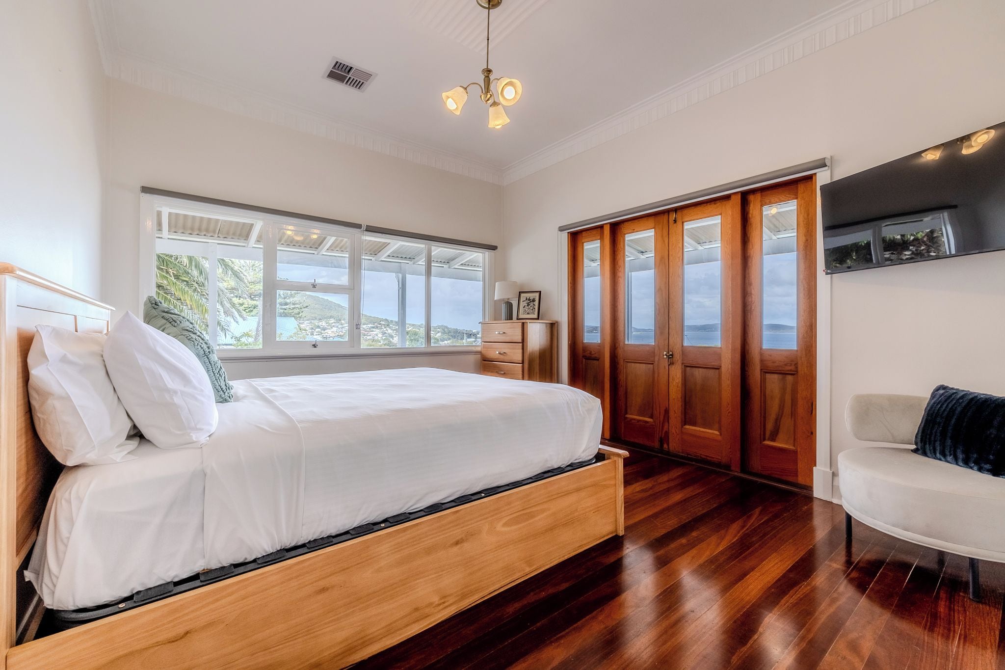 Quarto com cama, cadeira, guarda-roupa e vista para o exterior.