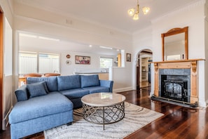 A spacious living room with a blue sectional sofa, a round coffee table, and a fireplace.