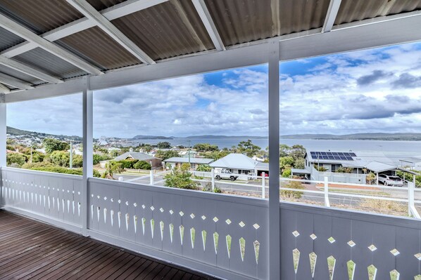 A covered outdoor area with a view of a coastal town, including houses and a body of water. - Blue Horizon by The BNB Collection (Albany)