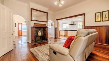 A spacious living room with a fireplace, a sofa, and a kitchen in the background.