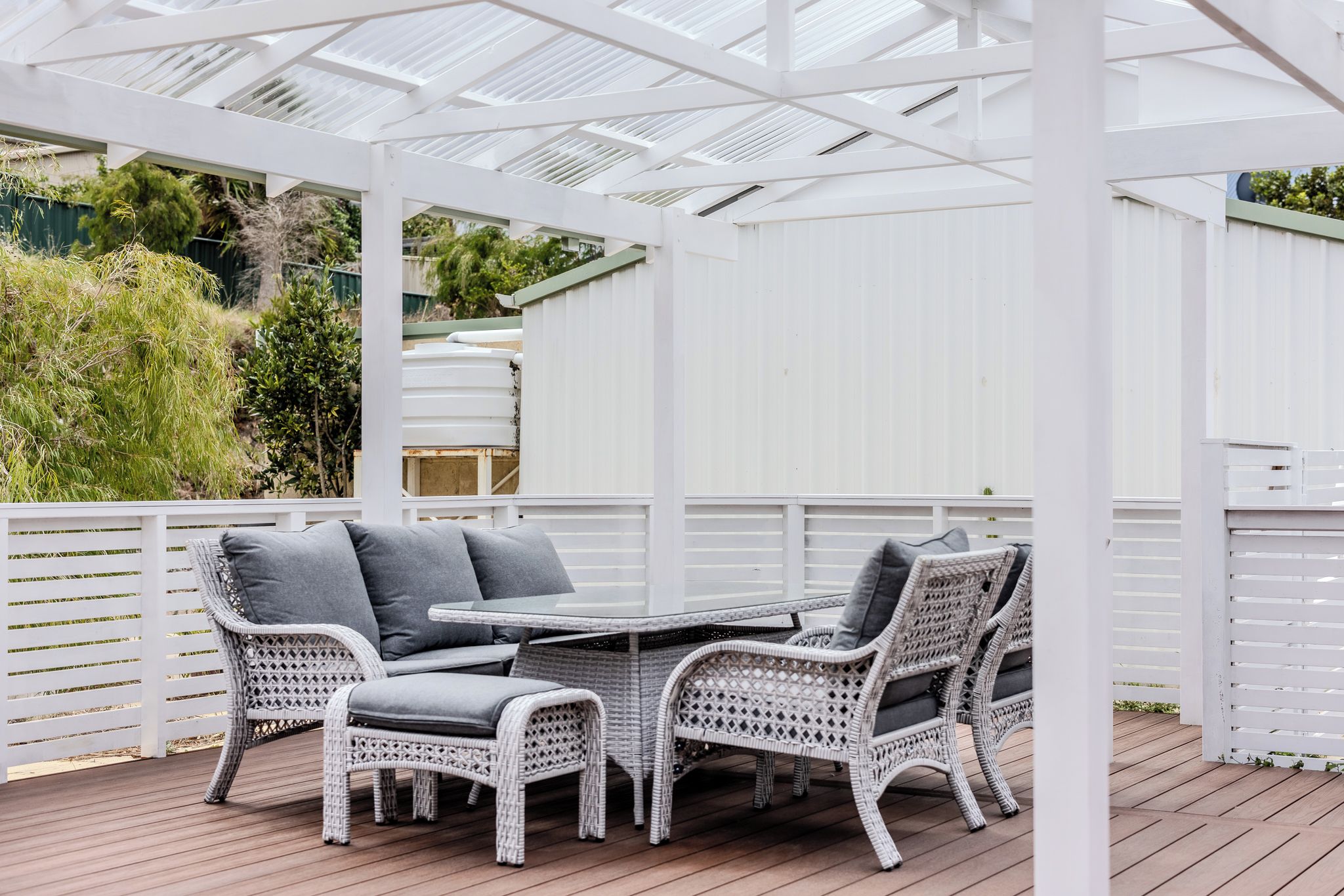 A covered outdoor seating area with wicker furniture and a table.