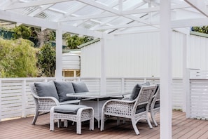 An outdoor patio with a white pergola, wicker furniture, and a table.