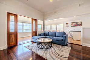 A spacious living room with a blue sofa, a round coffee table, and a patterned rug.