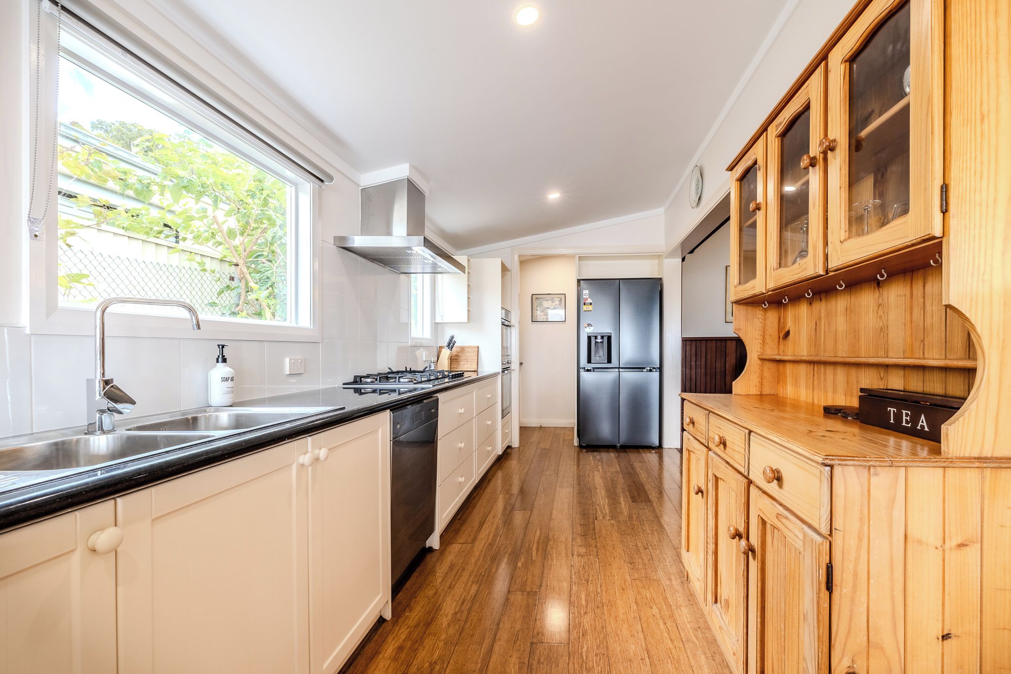 A modern kitchen with a stainless steel sink, a built-in oven, and a refrigerator.