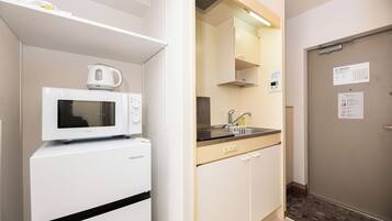 A compact kitchenette with a microwave, a small refrigerator, and a sink.