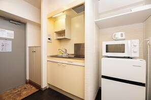 Una kitchenette compacta con microondas, pileta y un mueble pequeño.
