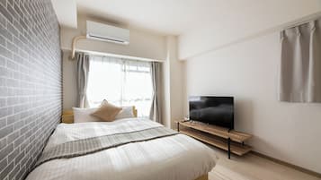 A modern hotel room with a large bed, a flat-screen TV, and an air conditioning unit.