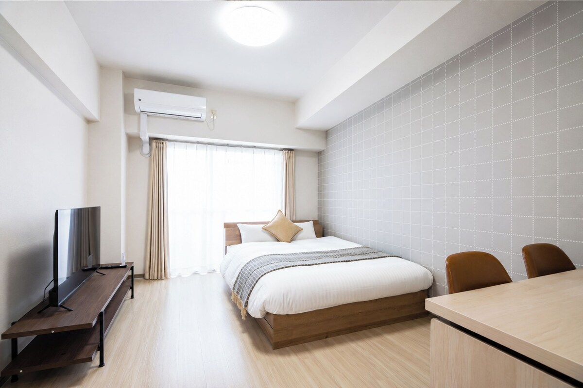 A hotel room with a bed, a TV, a desk, and a chair.