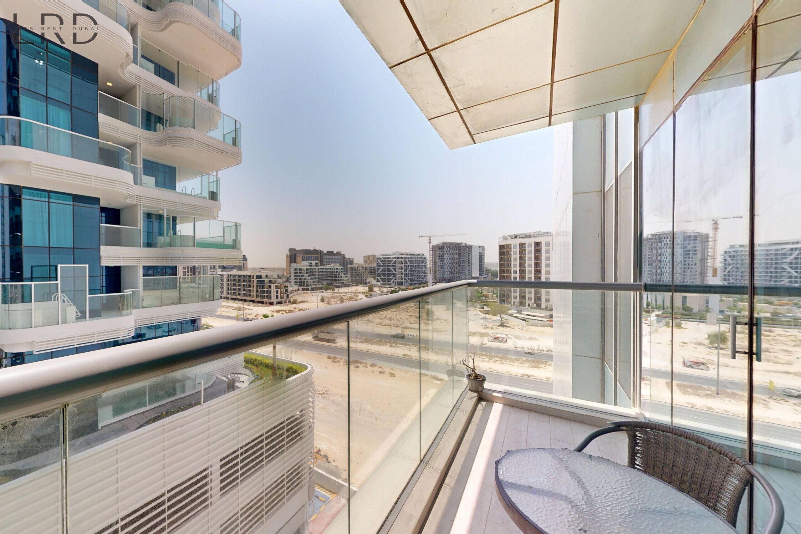 Un immeuble moderne de grande hauteur, doté de nombreux balcons, de grandes fenêtres et offrant une vue sur le paysage urbain environnant.