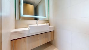 Ein modernes Badezimmer mit einem weißen Waschbecken, einer Holzwaschtischplatte und einem großen Spiegel.