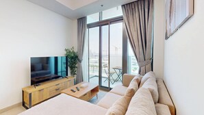Ein modernes Hotelzimmer mit einem großen Flachbildfernseher, einer Sitzecke, einem Holztisch und einem Balkon mit Stadtblick.
