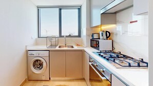 A compact kitchen with a built-in washer, a gas stove, and a microwave.