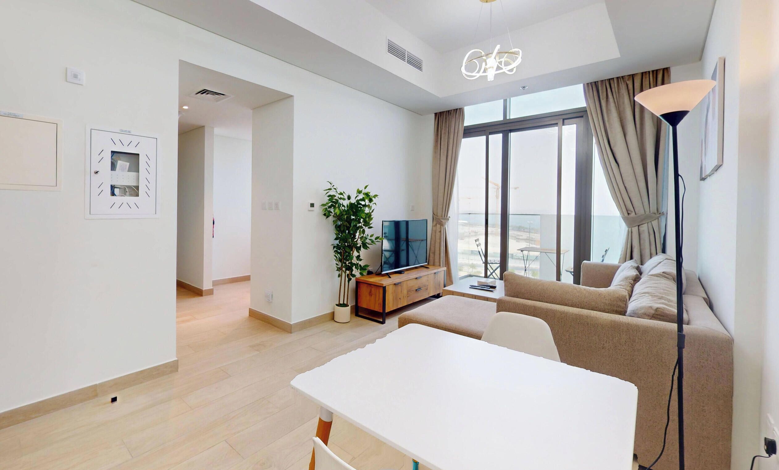 A modern living room with a sofa, a TV, and a dining table.