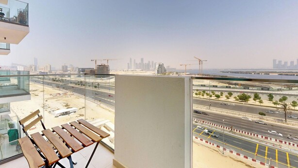 Un balcon offrant une vue sur le paysage urbain, avec notamment une autoroute et des grues de chantier.
