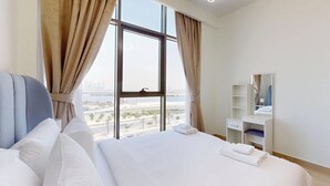 Une chambre d’hôtel avec un grand lit, une table de chevet, un miroir et une vue sur le paysage urbain par la fenêtre.