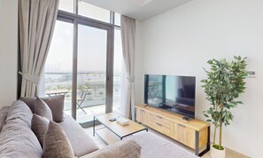 A modern living room with a sofa, a flat-screen TV, a coffee table, and a potted plant. - Chic 1BR with Canal View (Dubai)