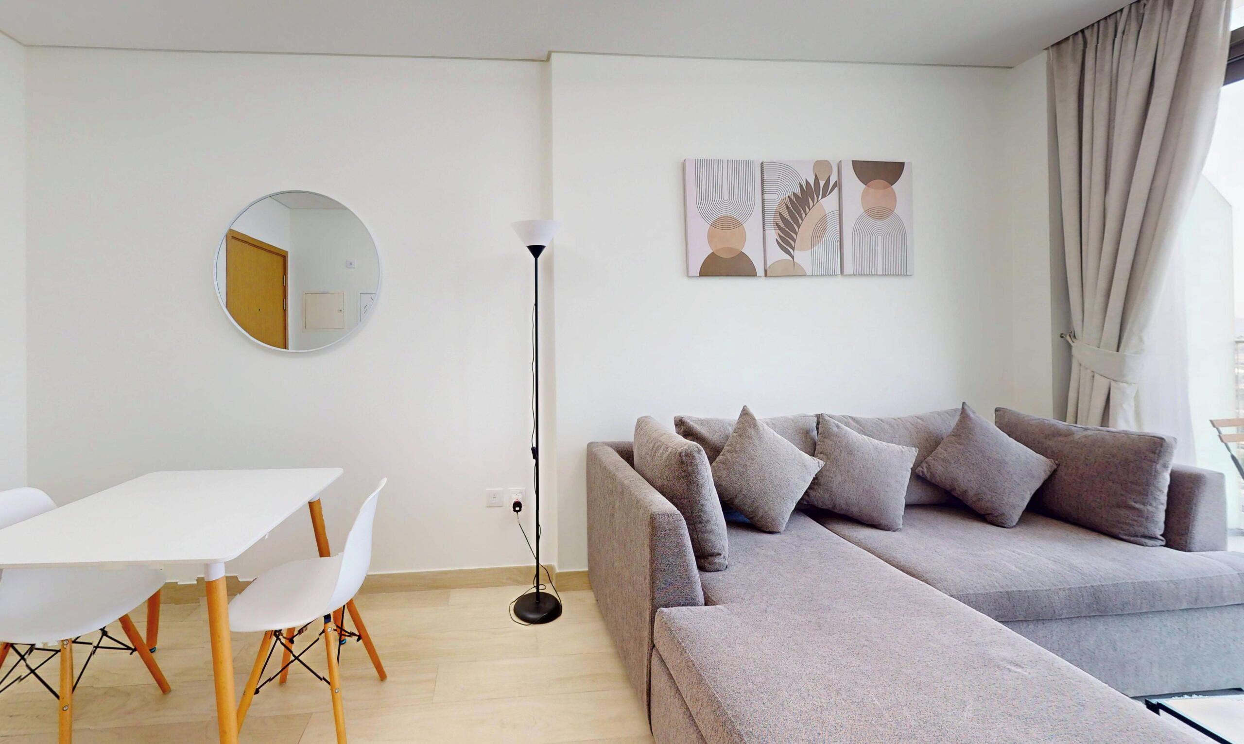 Ein modernes Wohnzimmer mit einer Couch, einem Esstisch mit Stühlen, einer Stehlampe und Bildern an der Wand.