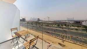 A balcony with a view of a busy road and a distant city skyline. - Chic 1BR with Canal View (Dubai)