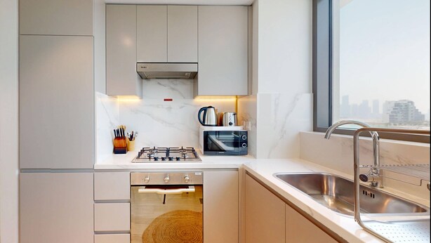 A modern kitchen with a built-in oven, microwave, and gas stove. - Chic 1BR with Canal View (Dubai)