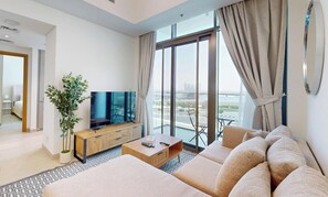 A modern hotel room with a large flat-screen TV, a sofa set, a wooden coffee table, and a potted plant. - Modern 1BR with Canal View (Dubai)