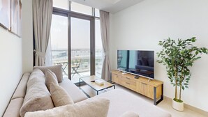 Ein modernes Wohnzimmer mit einer Couch, einem Couchtisch, einem Fernseher und einer Pflanze.
