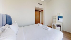A hotel room with a bed, a desk, a mirror, and a door leading to another room.