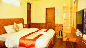 Una habitación de hotel con una cama de madera, un televisor, un armario de madera y una puerta.
