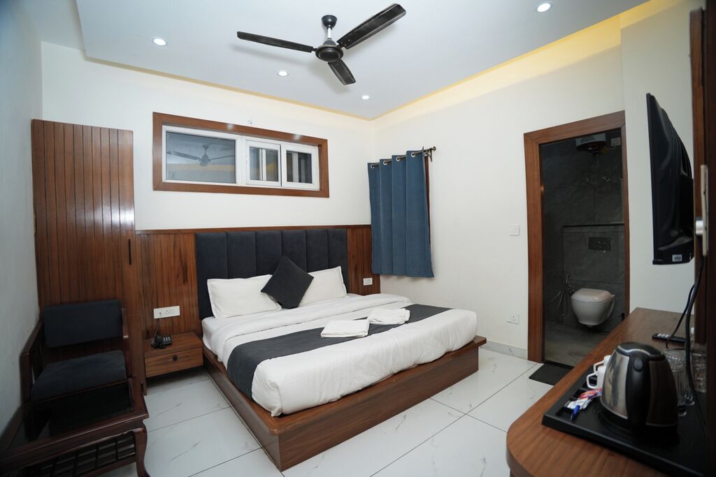Une chambre d’hôtel équipée d’un lit, d’un bureau, d’une télévision et d’un ventilateur de plafond.