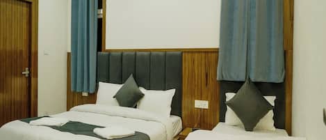 Habitación de hotel con dos camas, cabeceros de madera y cortinas azules.