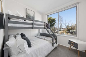 Un lit superposé avec un bureau et une fenêtre dans une chambre.
