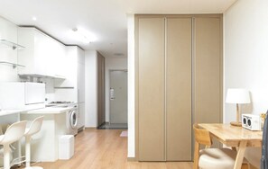 Une cuisine moderne équipée d’un lave-linge, d’un coin repas avec une table et des chaises, et d’un placard à portes coulissantes.
