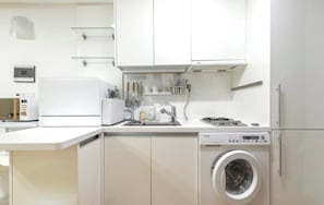 Une cuisine compacte équipée d’un lave-linge, d’un four à micro-ondes et d’un grille-pain.