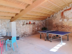 A ping pong table in a room with a rustic stone wall and wooden beams.