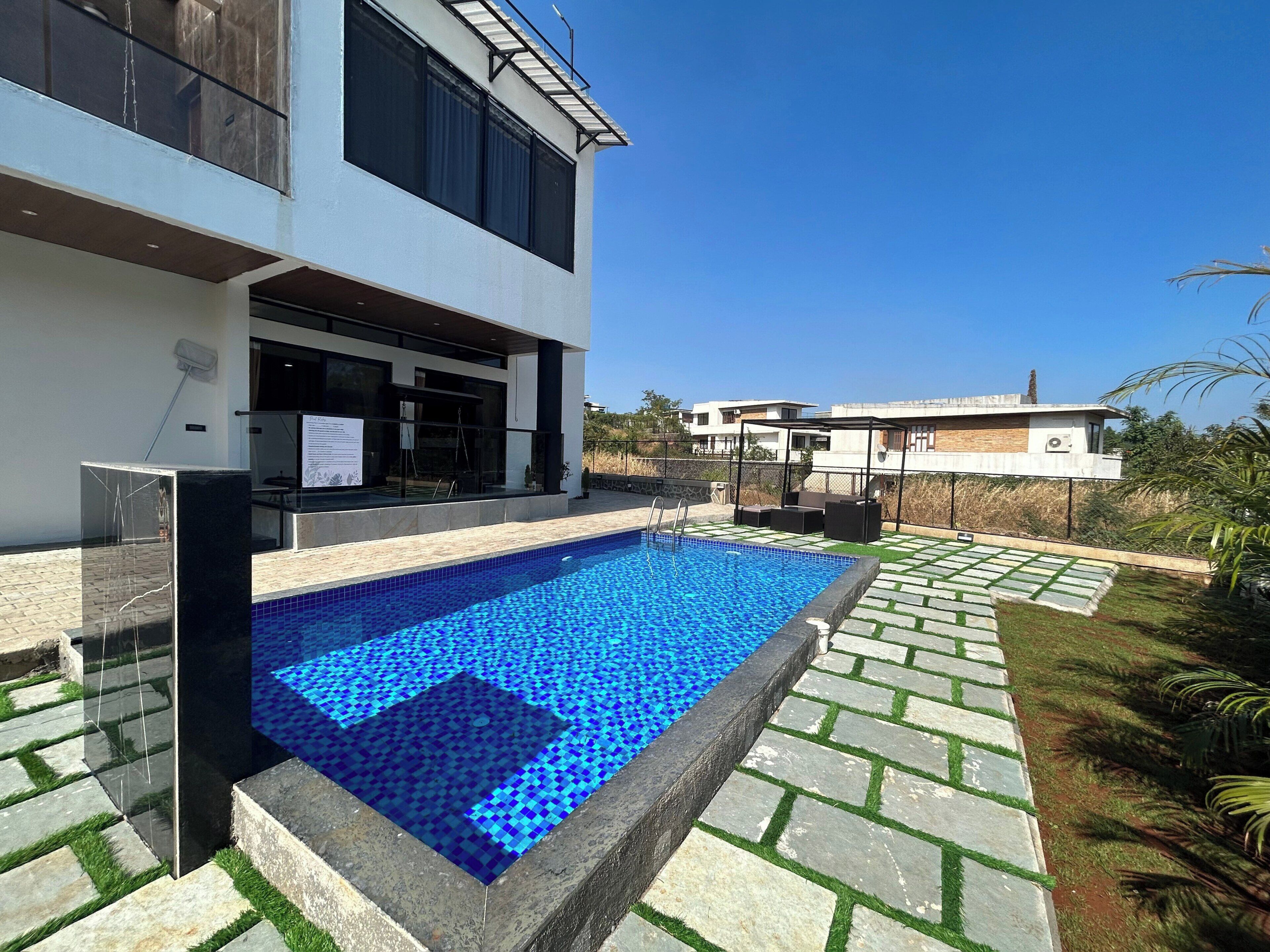 Un edificio moderno con piscina, asientos exteriores y cielo despejado.