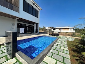 Een modern gebouw met een zwembad, terras en heldere lucht.