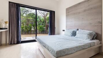 A bedroom with a bed, a nightstand, and a view of a garden through a sliding door.