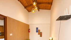 A wooden staircase with a handrail, a ceiling with wooden beams, and a wall-mounted light fixture.