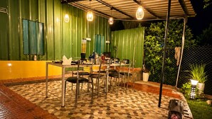 An outdoor patio area with hexagonal patterned flooring, metal chairs, a table, and a grill.