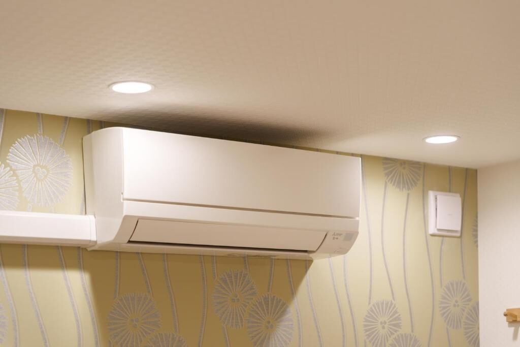 A room with a wall-mounted air conditioner and a power outlet.