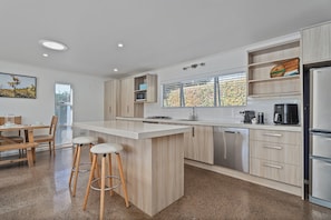 Eine moderne Küche mit einer zentralen Kochinsel, Barhocker, einem eingebauten Backofen und einem Edelstahl-Kühlschrank.