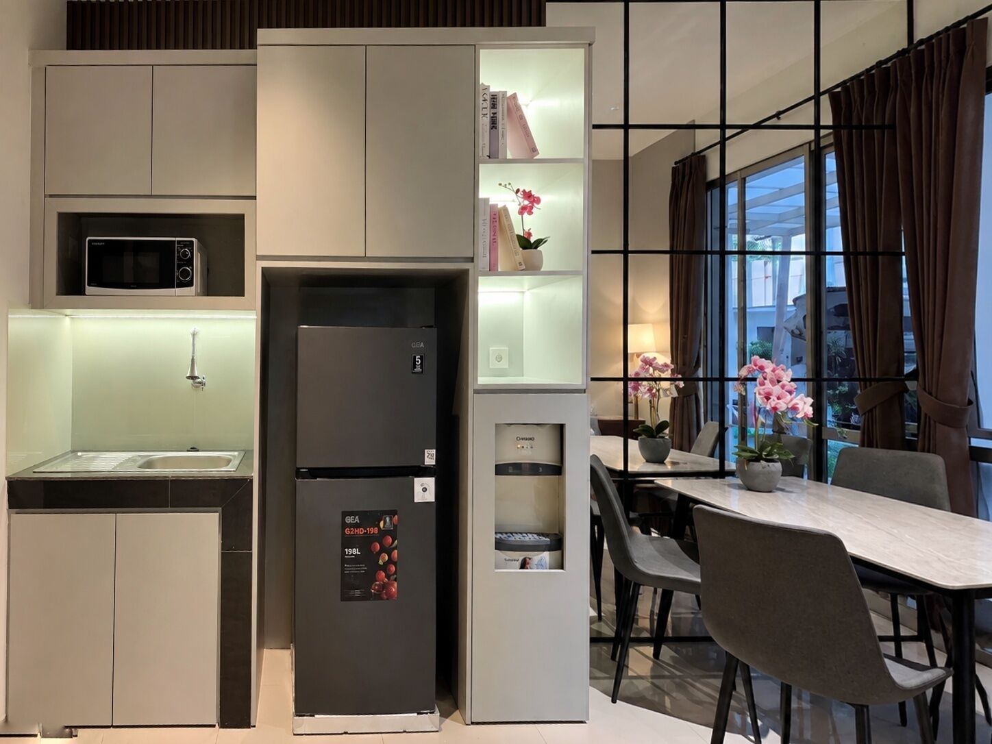 A compact kitchen with a built-in microwave, a refrigerator, and a dining area with a table and chairs.