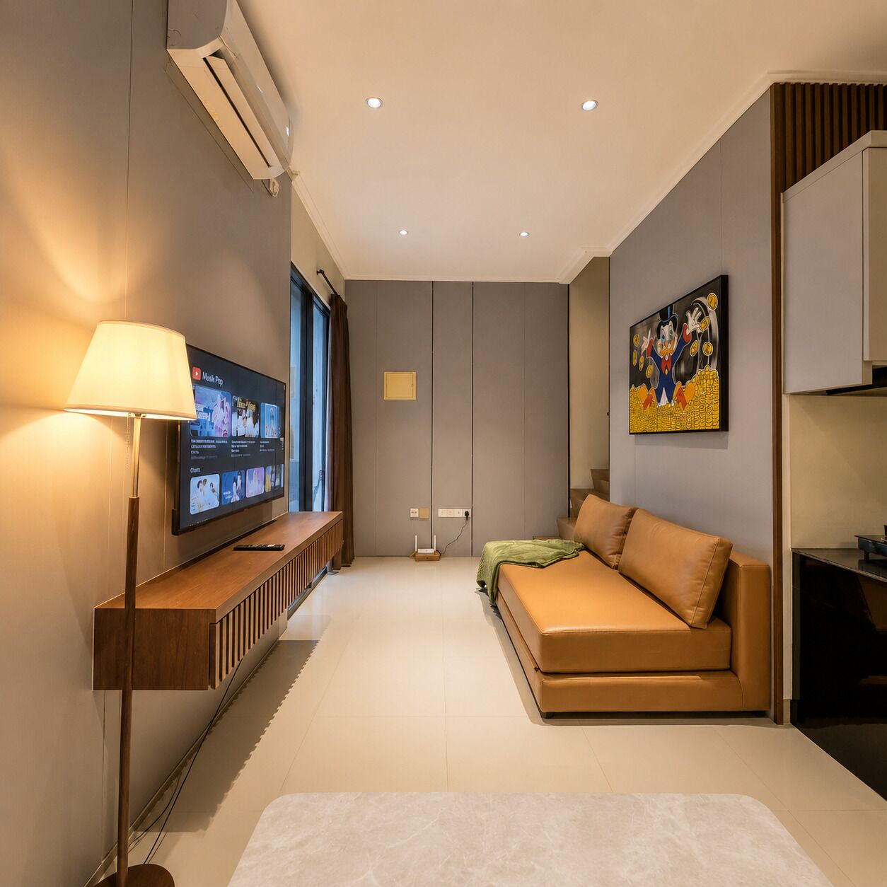 A modern living room with a flat-screen TV, a sofa, a lamp, and a painting on the wall.