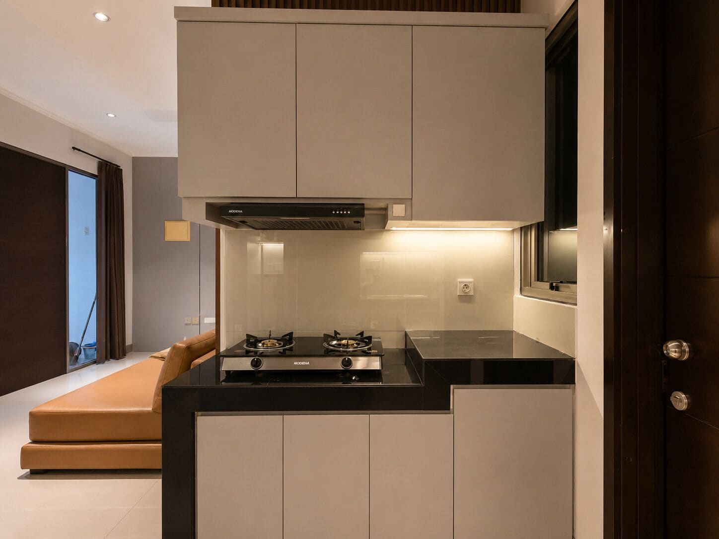 Una cocina compacta con estufa a gas, extractor de humos y horno integrado.