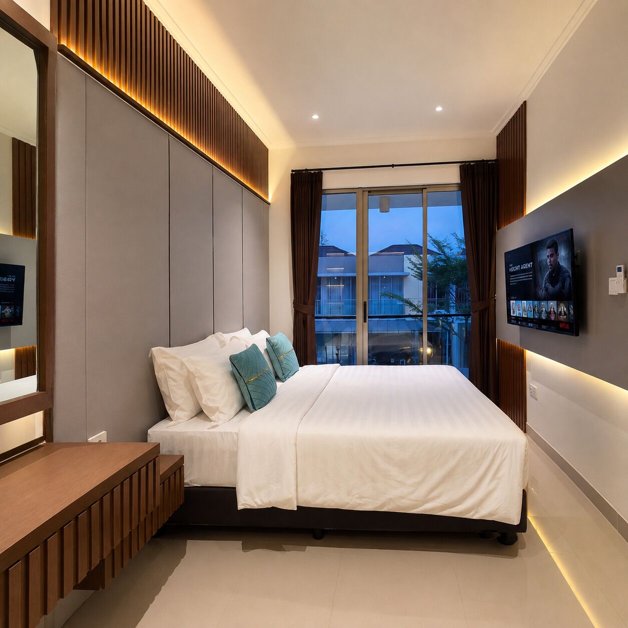 A modern bedroom with a bed, a TV mounted on the wall, and a window with curtains.