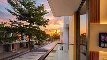 A modern building with a glass balcony overlooking a street at sunset.