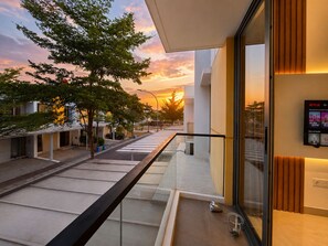 A modern building with a glass balcony overlooking a street at sunset. - LaBriza By SanLiving - 2BR - PIK2 (Kosambi)